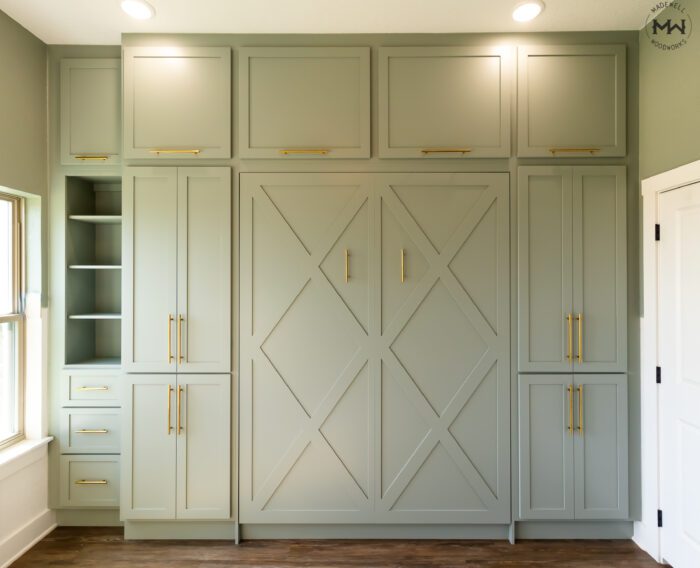 Queen Crestview built-in Murphy bed with storage cabinets and open shelving, sage green finish with gold pulls, installed in Austin TX by Madewell Woodworks