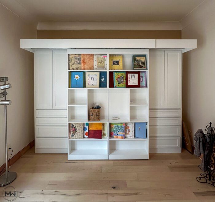 Built-in sliding bookcase Murphy bed with wardrobe cabinets in white, installed in Travis Heights Austin TX by Madewell Woodworks