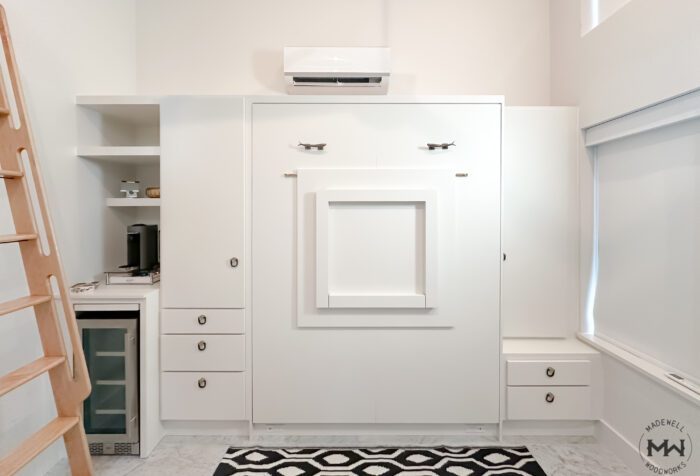 Custom white Murphy bed with folding dek front, built-in drawers, and beverage nook, handcrafted by Madewell Woodworks in Austin, Texas.