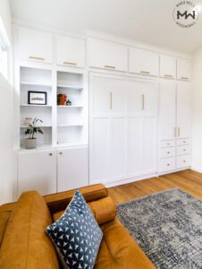 White Craftsman queen-size Murphy bed with gold hardware and built-in cabinetry, handcrafted by Madewell Woodworks in Austin, Texas.