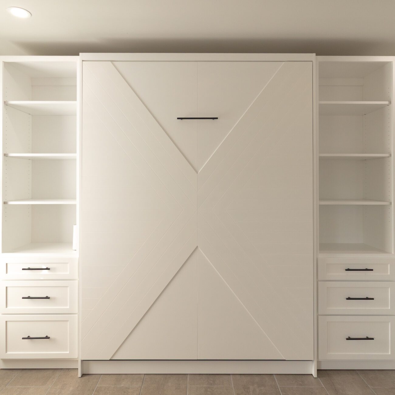 White Enfield Murphy bed with built-in shelving and black hardware, handcrafted by Madewell Woodworks in Austin, Texas.