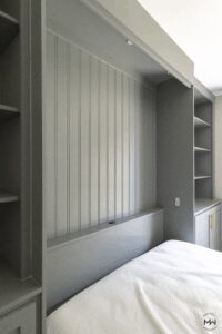 Custom green Murphy bed with vertical beadboard paneling and built-in shelving, handcrafted in Austin by Madewell Woodworks.