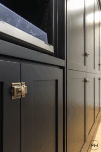 Close-up of black custom Murphy bed cabinetry with brass latch hardware and record player shelf.