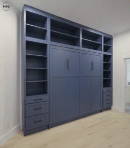 King-size Craftsman-style Murphy bed in deep navy with full-height built-in shelving and lower cabinetry, handcrafted in Austin, Texas.
