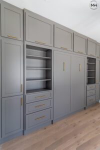 Custom light brown built-in Murphy bed wall with brass hardware and storage cabinetry, handcrafted in Austin by Madewell Woodworks.