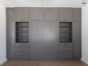 Custom brown wall-to-wall Murphy bed system with brass hardware and built-in shelving, handcrafted in Austin by Madewell Woodworks.