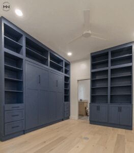 Deep navy Craftsman-style Murphy bed with full-height built-in shelving and lower storage drawers, handcrafted in Austin, Texas.