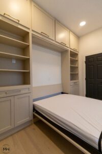 Custom neutral-tone Murphy bed with built-in shelving and cabinetry, handcrafted in Austin by Madewell Woodworks.
