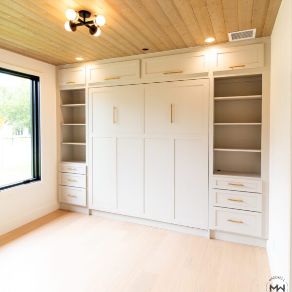 Custom neutral Craftsman-style Murphy bed with built-in shelving and gold hardware, handcrafted in Austin by Madewell Woodworks.