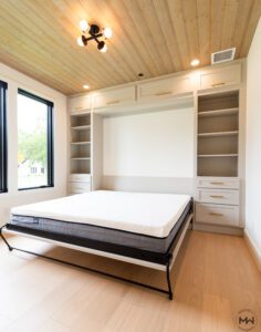 Custom King Murphy bed shown open, featuring neutral cabinetry with built-in shelving and upper storage, handcrafted in Austin by Madewell Woodworks.