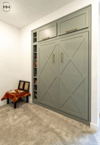 Custom sage green Murphy bed with Crestview trimmed doors and built-in shelving, handcrafted in Austin by Madewell Woodworks