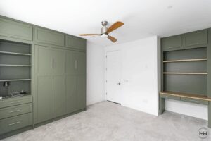 Sage green Murphy bed with matching built-in desk and shelving, handcrafted by Madewell Woodworks in Austin, Texas.