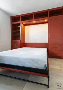 Red Shaker Murphy bed with built-in lighting, drawers, and shelving, handcrafted by Madewell Woodworks in Austin, Texas.