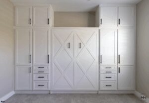 White Crestview-style Murphy bed with geometric paneling and full-height cabinetry, accented with matte black hardware.