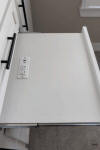 White custom nightstand with integrated powered grommet featuring USB and outlet ports.