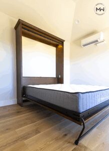 Custom maple Murphy bed with chevron barn-door design shown open, featuring soft integrated lighting and a clean, natural wood finish by Madewell Woodworks in Austin.