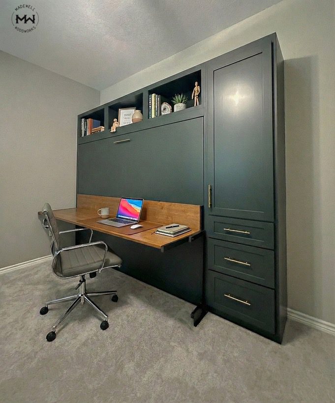 Modern deep green horizontal Murphy bed with integrated desk, open shelving, and side storage drawers in a home office.