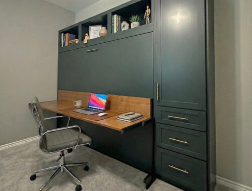 Modern deep green horizontal Murphy bed with integrated desk, open shelving, and side storage drawers in a home office.