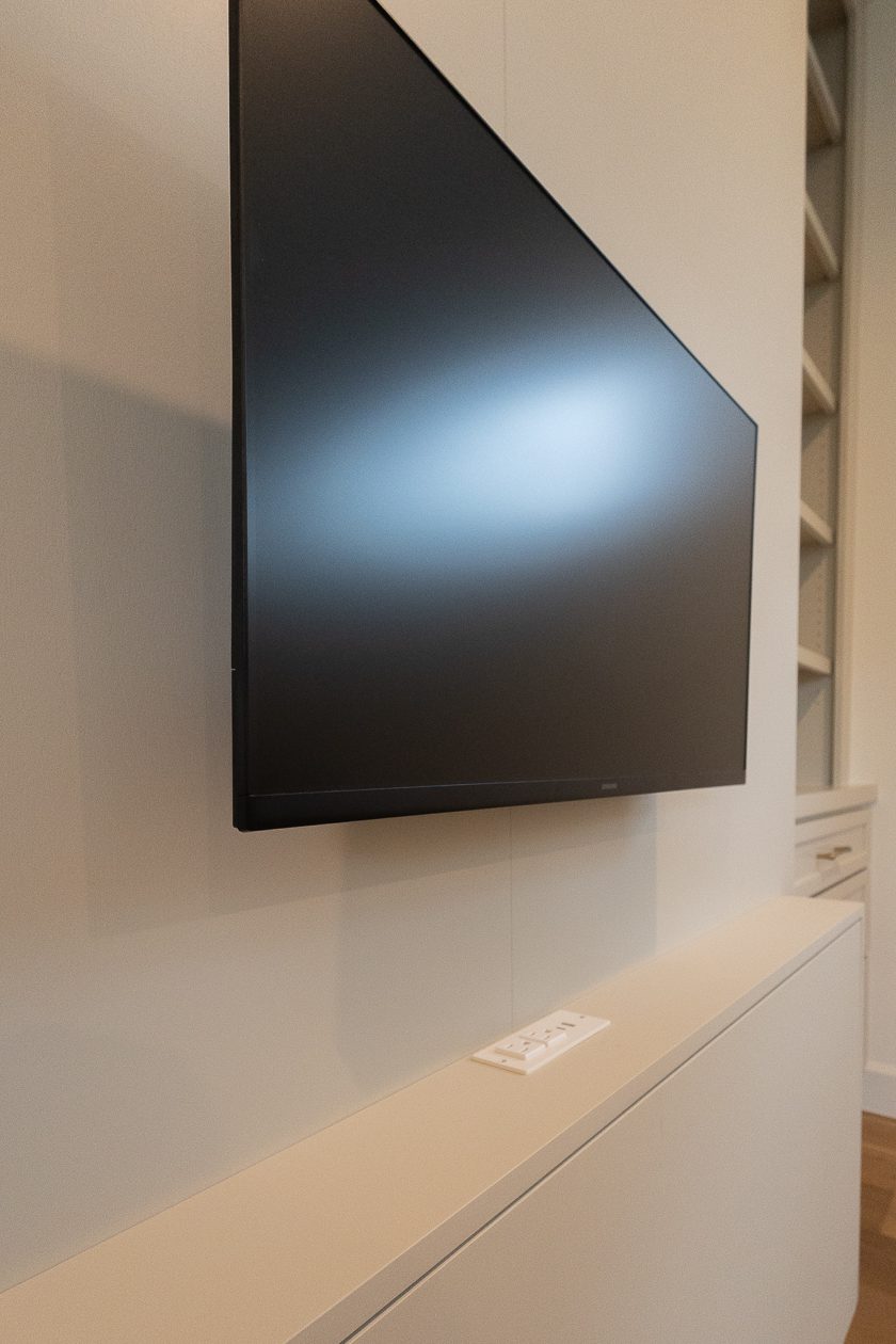 Wall-mounted monitor on Murphy bed face with powered outlet below in built-in cabinetry