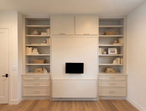 Revere Pewter Velar Murphy bed with upper cabinets, styled open shelving, drawer stacks, and wall-mounted monitor in Northwest Hills Austin