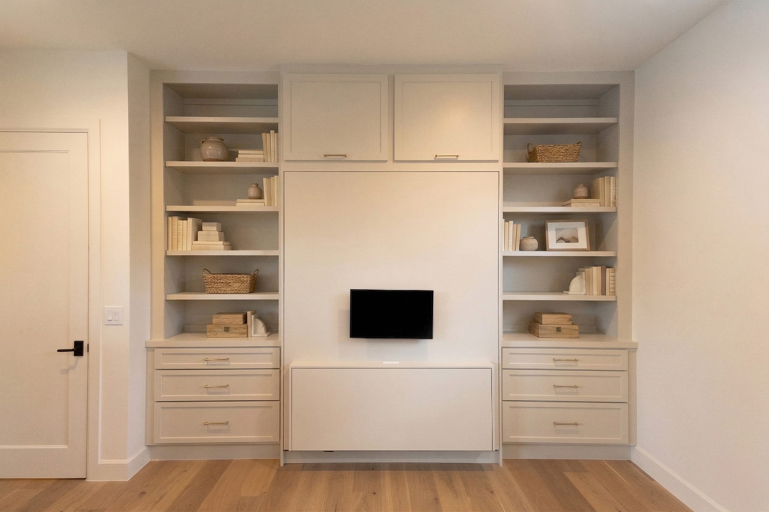 Revere Pewter Velar Murphy bed with upper cabinets, styled open shelving, drawer stacks, and wall-mounted monitor in Northwest Hills Austin