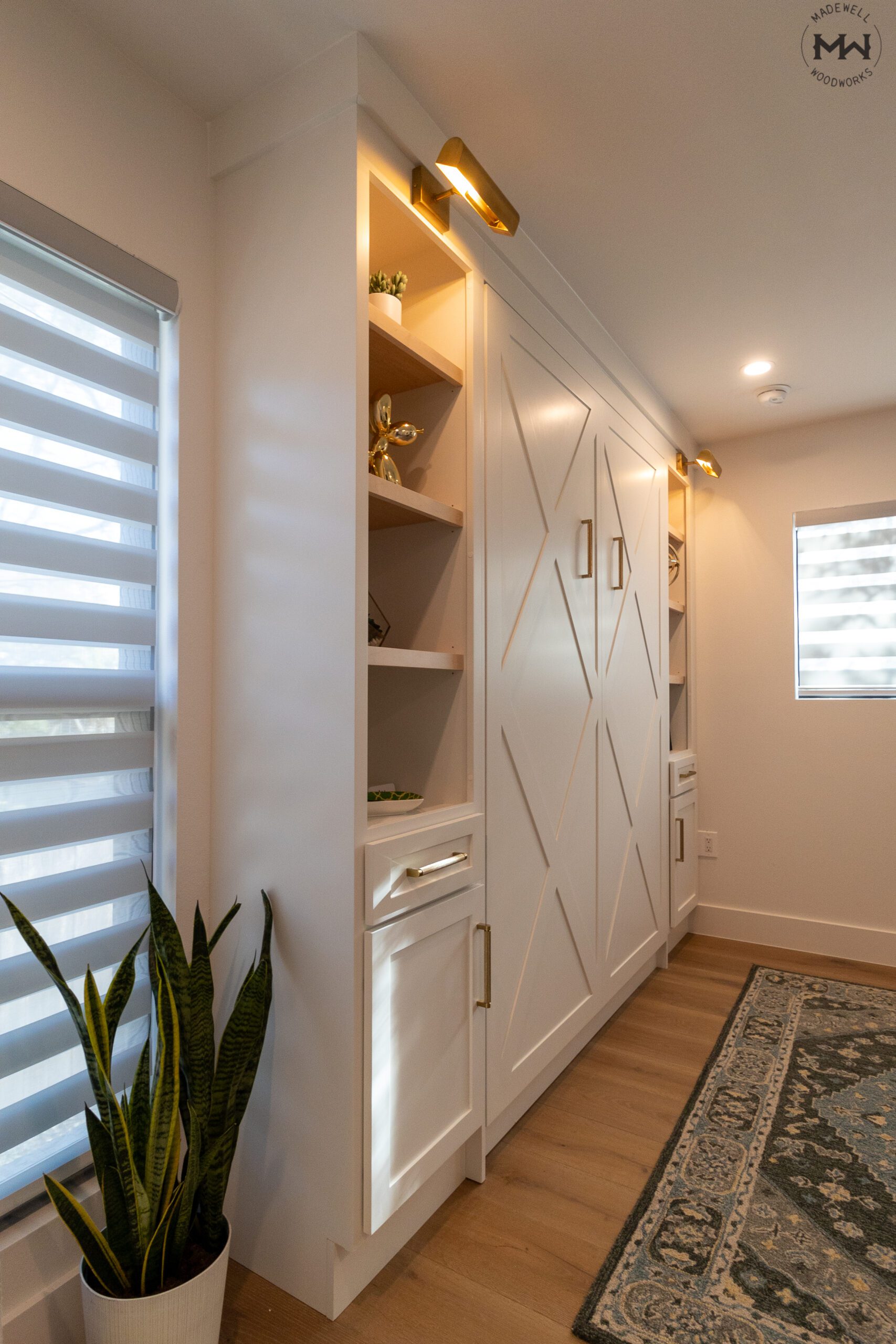 Detail of lit open shelving tower on Crestview Murphy bed, Super White finish with gold sconce lighting and gold pulls, Northwest Hills Austin TX