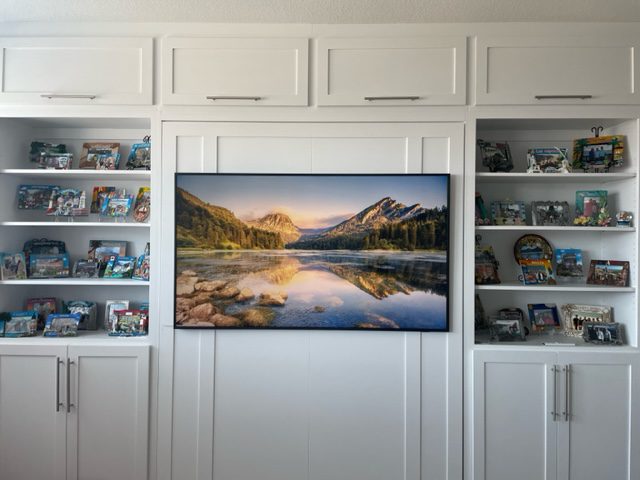 Queen vertical Rivington Murphy bed stowed with Samsung Frame TV mounted to bed face, open shelving towers with collectibles, Super White finish, Avery Ranch Austin TX