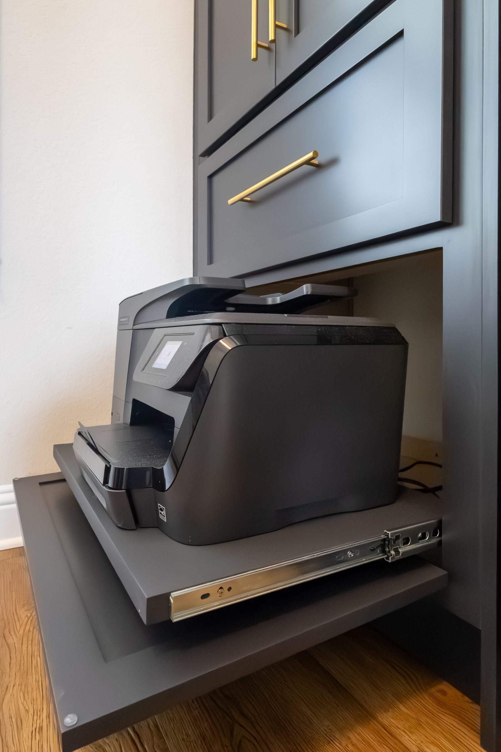 Built-in lower cabinet with pull-out printer shelf and gold bar handles, part of custom Murphy bed system in Austin, TX